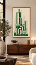 Load image into Gallery viewer, A framed vertical art print featuring a green industrial skyline illustration labeled 'Houston' on an off-white background, displayed on a beige wall above a wooden console in a styled living room.